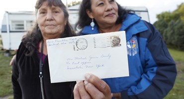 Two women holding a letter addressed to Mr Brody