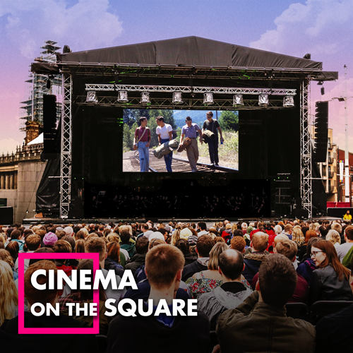 A crowd sits in front of a large screen on stage, in front of a dusky sunset sky. Text reads: Cinema on the Square